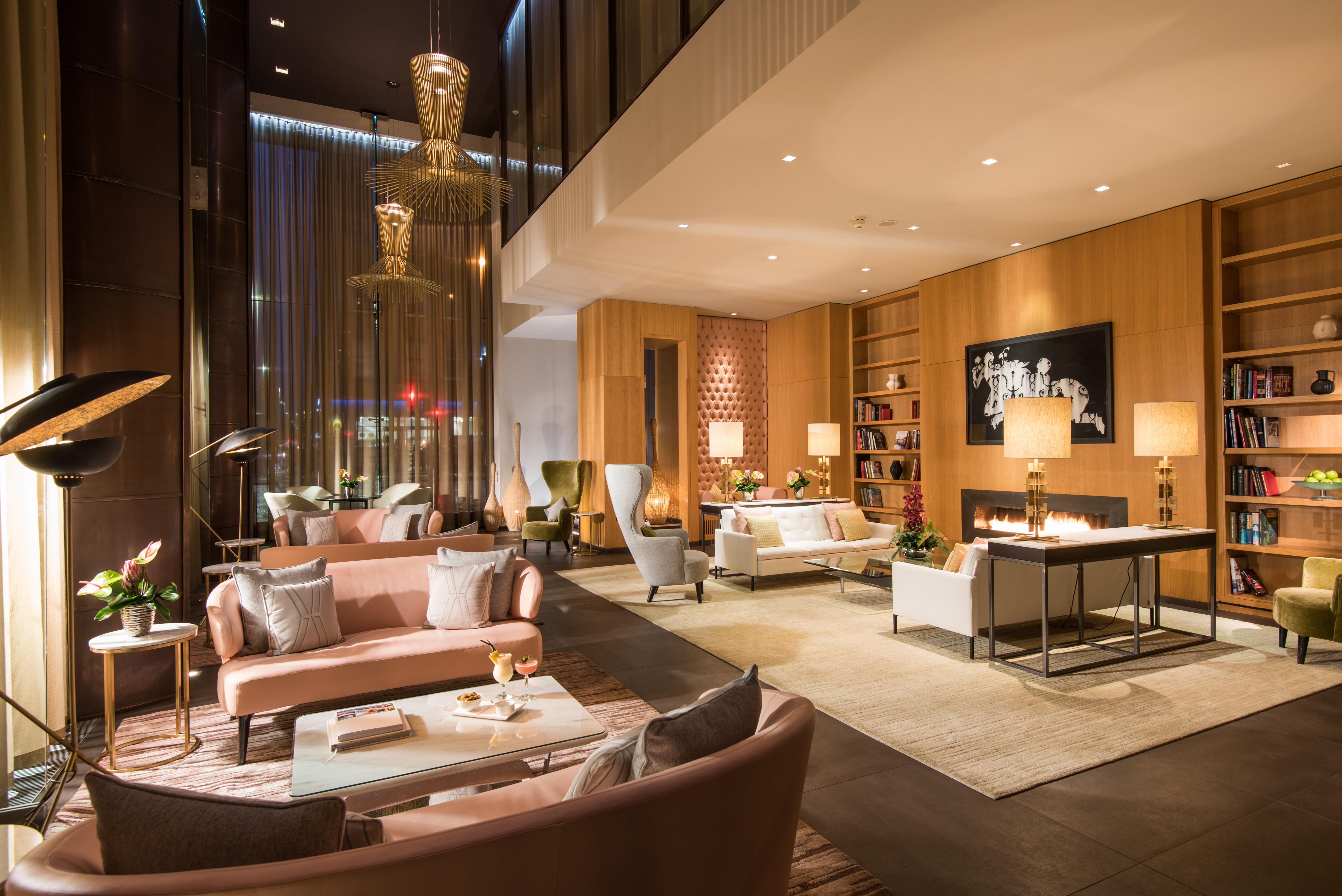 The Fitzwilliam Hotel Belfast Exterior foto The photo shows a modern and elegant lobby or lounge area. The space features a mix of contemporary and cozy furniture, including light-colored sofas and armchairs arranged around small tables. There are decorative elements like vases with flowers, a